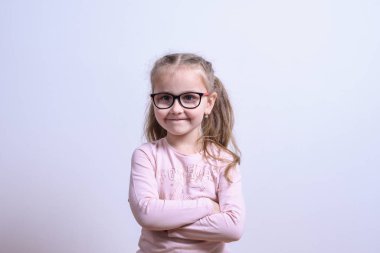 Gri arka planda gülümseyen küçük beyaz bir kızın portresi.