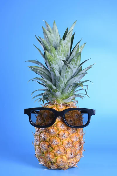 Ananas in Sonnenbrille in Großaufnahme auf blauem Hintergrund — Stockfoto