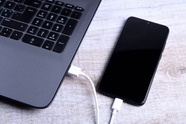 Usb kablosu, kablolu şarj aleti, şarj, şarj edilmiş ve veri transferi cep telefonu, ahşap zemin üzerinde dizüstü bilgisayarı olan akıllı telefon, masa üstü görünümü