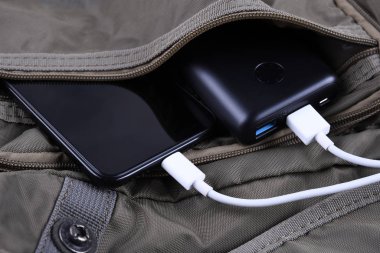 Telefon şarjı, elektrik faturası akıllı telefon, enerji bankasıyla cep telefonu. Sırt çantasındaki Güç Bankası alanının derinliği