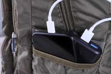 Telefon şarjı, elektrik faturası akıllı telefon, enerji bankasıyla cep telefonu. Sırt çantasındaki Güç Bankası alanının derinliği