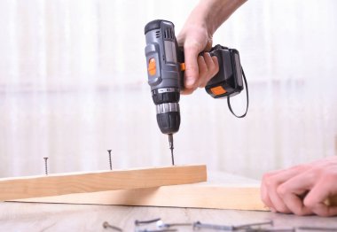 Adam yeni ev kurulumunda Elektrikli tornavida kullanarak mobilya montaj ile çalışma - teknisyen yerinde işe el araçları kavramı kullanma