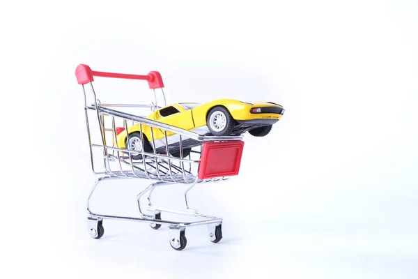 Concept van het kopen van een nieuwe auto. Speelgoedauto in mandje geïsoleerd op witte achtergrond — Stockfoto