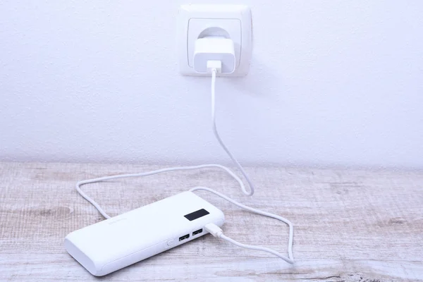 Блок живлення білого телефону, підключений до гнізда на стіні для зарядки на дерев'яному фоні — стокове фото