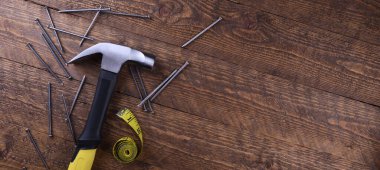 Çekiç demiri, santimetre bant ve tahta zeminde çiviler.