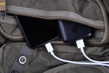 Telefon şarjı, elektrik faturası akıllı telefon, enerji bankasıyla cep telefonu. Sırt çantasındaki Güç Bankası 'nın derinliği