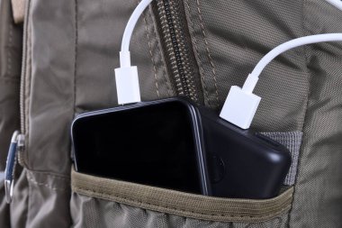 Telefon şarjı, elektrik faturası akıllı telefon, enerji bankasıyla cep telefonu. Sırt çantasındaki Güç Bankası 'nın derinliği