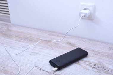 Siyah telefon şarj etmek için prize takılı.