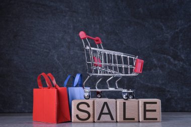 Alışveriş konsepti. Koyu arka planda, alışveriş sepetli ahşap küpler.