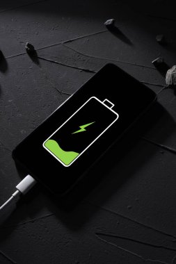 Üst Manzara. Telefon, akıllı telefon koyu betondan yapılmış, arka planda koyu gölgeler var.