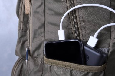 Telefon şarjı, elektrik faturası akıllı telefon, enerji bankasıyla cep telefonu. Sırt çantasındaki Güç Bankası 'nın derinliği