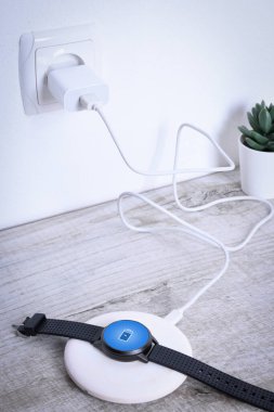 Kablosuz şarj göstergesiyle çalışan akıllı saat. Masaüstünde, dizüstü bilgisayarın yanında. Üst Manzara. Metin için yer