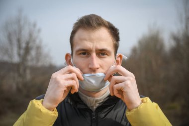 Kendini tıbbi maske takan çekici bir gencin portresi..