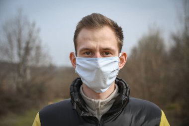 Kendini tıbbi maske takan çekici bir gencin portresi..