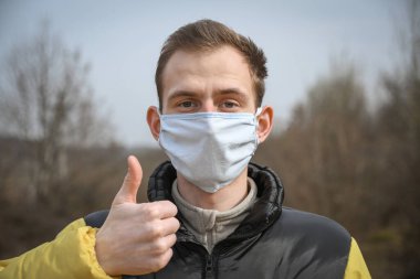 Kendini tıbbi maske takan çekici bir gencin portresi..