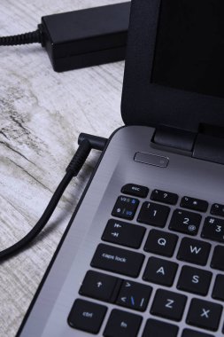 Laptop, bilgisayar duvarın yanındaki bir masada 220 voltluk bir prizden şarj oluyor. Enerji, birikim