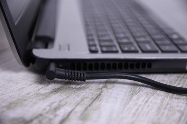 Laptop, bilgisayar duvarın yanındaki bir masada 220 voltluk bir prizden şarj oluyor. Enerji, birikim