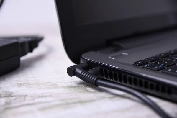 Laptop, bilgisayar duvarın yanındaki bir masada 220 voltluk bir prizden şarj oluyor. Enerji, birikim
