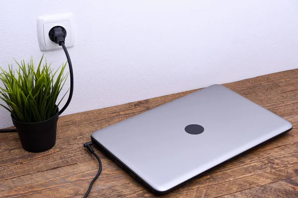 Laptop, bilgisayar duvarın yanındaki bir masada 220 voltluk bir prizden şarj oluyor. Enerji, birikim