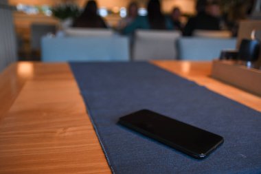 Kafedeki masanın üstünde güzel, bulanık bir arka planı olan bir cep telefonu.