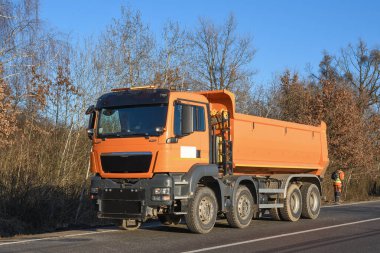 Bir kova kazıcı yol kenarını temizliyor. Yol çalışıyor. Yeni bir yol açıyorum. Kazı kil ve bir taş yükleniyor
