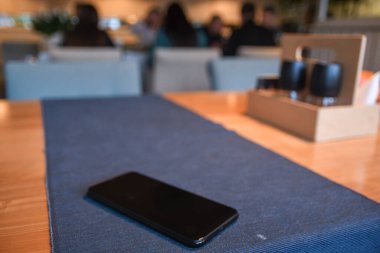 Kafedeki masanın üstünde güzel, bulanık bir arka planı olan bir cep telefonu.