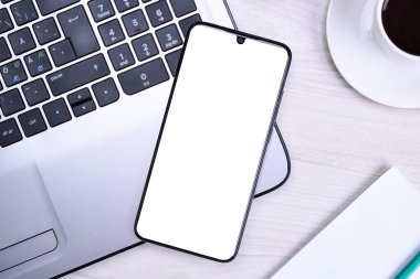 İşyerleri ahşap ofis masaları boş cep telefonları, çeşitli malzemeler. Okul, eğitim, teknoloji ve reklam konsepti. Model yap. Laptop akıllı telefon, bir fincan kahve.