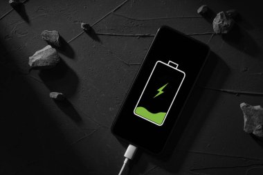 Üst Manzara. Telefon, akıllı telefon koyu betondan yapılmış, arka planda koyu gölgeler var.
