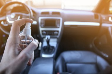 Arabanın içini dezenfeksiyon sıvısıyla temizliyorum. Direksiyon ve direksiyon kollarında dezenfeksiyon var. Coronavirus, Covid-19 koruma. İçerideki vihicle dezenfekte ediliyor..