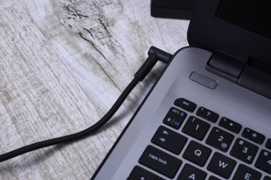 Laptop, bilgisayar duvarın yanındaki bir masada 220 voltluk bir prizden şarj oluyor. Enerji, birikim