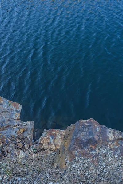 Stone rocks near water, on the background of lake, river, sea, ocean. Blue clear water. Artificial water reservoirs.