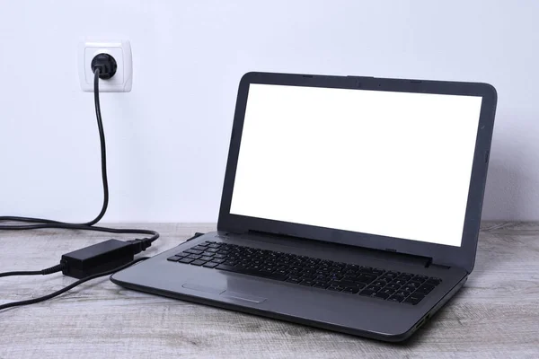 Laptop, bilgisayar duvarın yanındaki bir masada 220 voltluk bir prizden şarj oluyor. Enerji, birikim