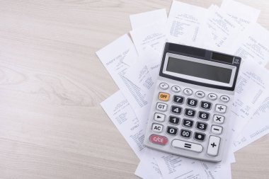 Ahşap bir arka planda, mağazadan gelen bir yığın çeke güvendiğin için hesap makinesi. Üst Manzara. Metin için yer. Boşluğu kopyala.