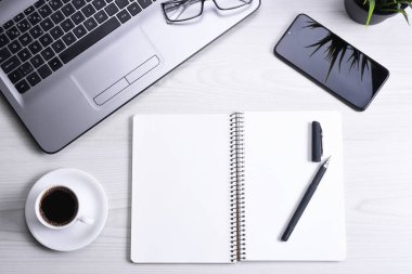 Ofis çalışma alanının en üst görüntüsü, dizüstü bilgisayarı, klavyesi, gözlükleri, telefonu ve bir fincan kahvesi olan tahta masa masası..