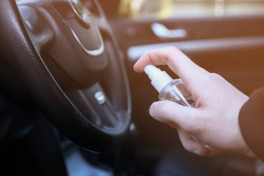 Arabanın içini dezenfeksiyon sıvısıyla temizliyorum. Direksiyon ve direksiyon kollarında dezenfeksiyon var. Coronavirus, Covid-19 koruma. İçerideki vihicle dezenfekte ediliyor..