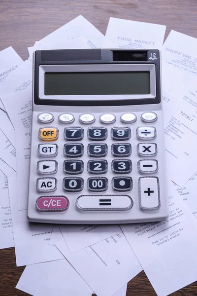 Calculator keypad with checks from the store from shopping on a wooden floor background. Top view. Copy space