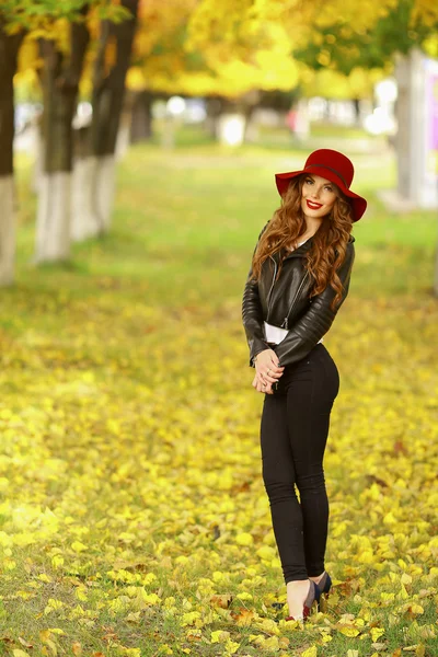 Bella donna elegante in piedi in cappello rosso alla moda in un parco in autunno . — Foto Stock