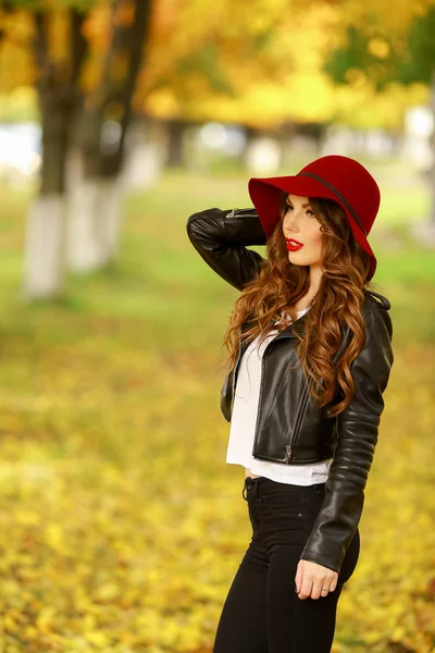 Красивая элегантная женщина, стоящая в модной красной шляпе в парке осенью . — стоковое фото