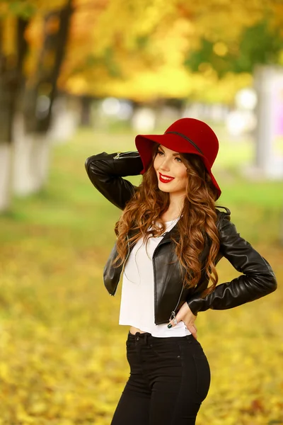 Bella donna elegante in piedi in cappello rosso alla moda in un parco in autunno . — Foto Stock