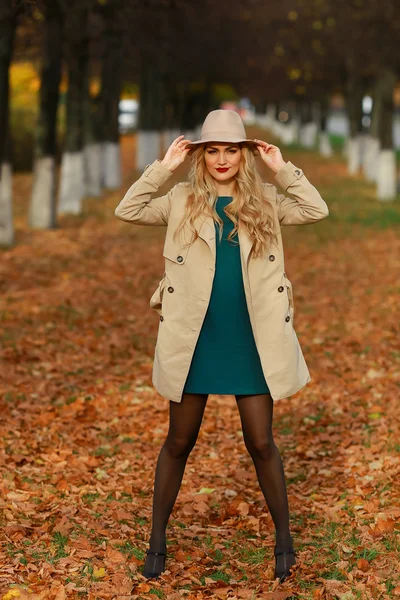 Bella donna elegante in piedi a tutta lunghezza in cappello beige alla moda in un parco in autunno . — Foto Stock