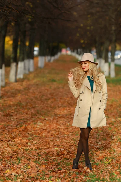 Красивая элегантная женщина, стоящая во всю длину в модной бежевой шляпе в парке осенью. Свободное место. концепция осень — стоковое фото