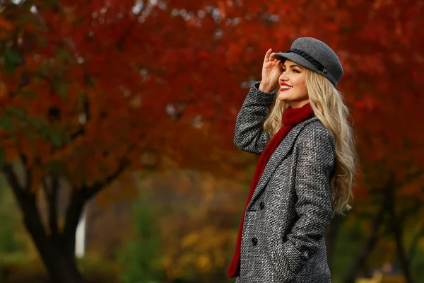 Молодая женщина улыбается на фоне красного сада. свободное место — стоковое фото