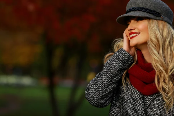 Schöne Frau lächelt im herbstlichen Park. roter Ahorn Garten Hintergrund. Blick nach links vom Rahmen zum leeren Kopierraum. — Stockfoto