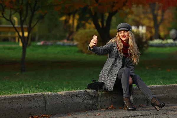 Bella ragazza prendere un autoritratto con il suo smartphone in autunno parco . — Foto Stock