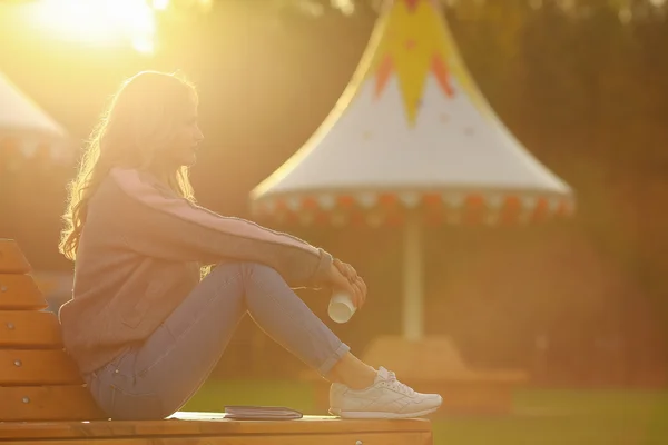 Jeune femme élégante buvant du café dans un parc. Belle fille au coucher du soleil . — Photo