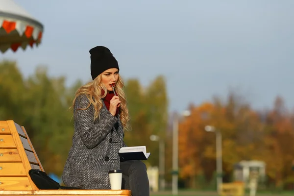 Jeune femme élégante travaillant dans un parc avec son stylo dans la bouche . — Photo