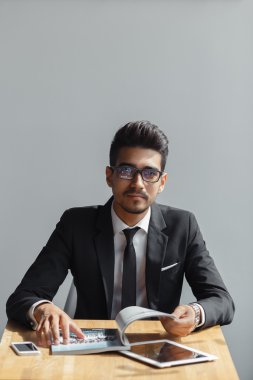 Yakışıklı genç işadamı kamera kafede otururken gri arka plan bakarak