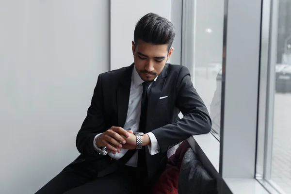 Επιχειρηματίας κάθεται σχετικά με παράθυρο και κοιτάζοντας το ρολόι του — Φωτογραφία Αρχείου