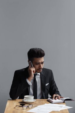 Güzel bir başarılı adam telefon ofis üzerinde konuşmak ve kafede bir defter yazma