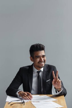 Gülümseyen ve bir işaret gösteren genç iş adamı, takım elbiseli, tamam
